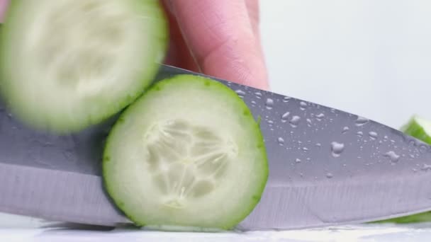 Het snijden van rauwe groene komkommer op een witte achtergrond. Close-up - Video