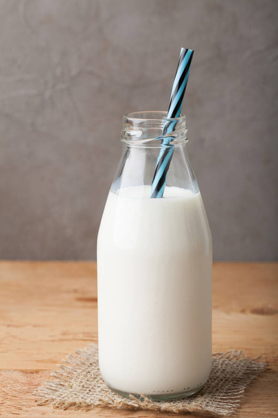 Bottle of milk on a wooden table over dark background with copy space - Photo, Image