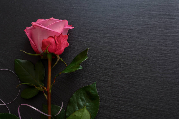 Kwiat różowy róż na czarny deska łupek, płytki, taca. Te hybrydowe - Zdjęcie, obraz