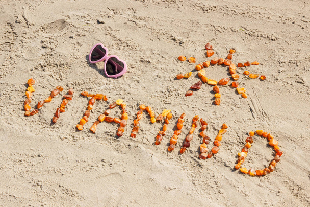 Sunglasses, inscription vitamin D and shape of sun on sand at beach, summer time and healthy lifestyle concept - Fotó, kép