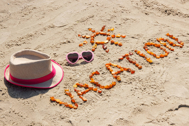 Word vacation with shape of sun sunglasses and straw hat on sand at beach - Φωτογραφία, εικόνα