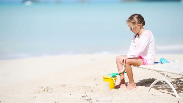 Rozkošná holčička hraje s hračkami na pláži dovolenou. Kid hry s pískem - Záběry, video