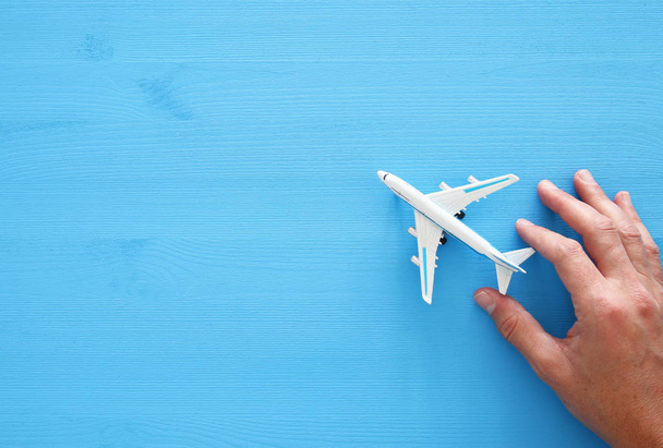 top view photo of man's hand holding toy airplane over blue wooden background. - Photo, image