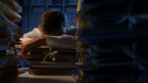Exhausto hombre de negocios sobrecargado de trabajo durmiendo en la oficina tarde en la noche en su escritorio, el trabajo de horas extras y el concepto de plazos
 - Metraje, vídeo