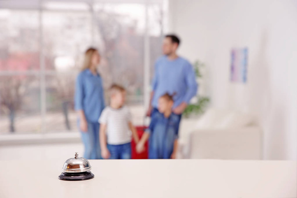 Hotel service bell on reception desk and blurred family on background - 写真・画像