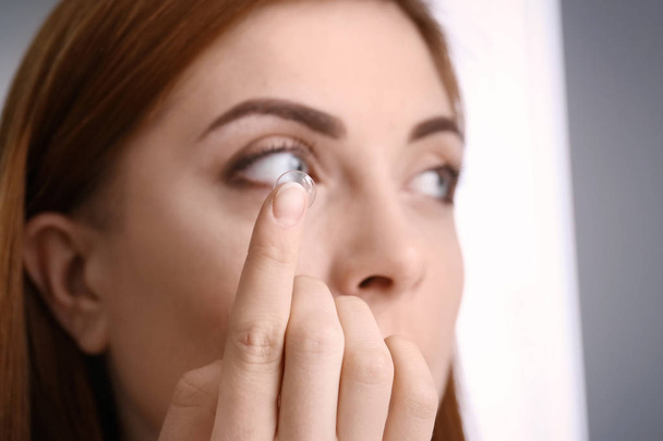 Mladá žena uvedení kontaktní čočky v oku, closeup - Fotografie, Obrázek