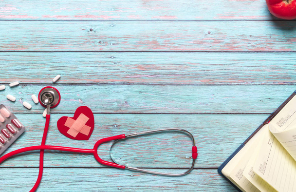 Sağlık ve tıp kavramı kırmızı stetoskop ve tıp mavi ahşap arka plan üzerinde - Fotoğraf, Görsel