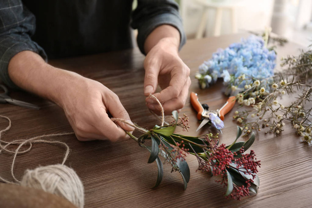 Male florist creating beautiful bouquet at table, closeup - Photo, image