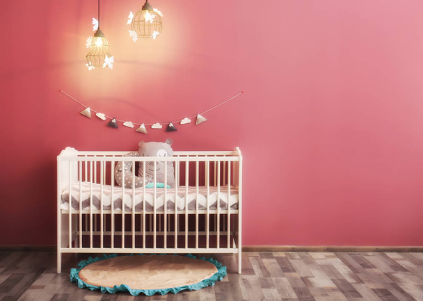 Modern baby room interior with crib near color wall - Фото, изображение