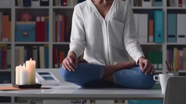 Woman sitting in the lotus position on the top of the desk and practicing meditation, mindfulness and healthy lifestyle concept - Filmagem, Vídeo