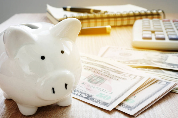 Savings or home budget concept. Calculator, dollar bills and piggy bank. - Fotoğraf, Görsel