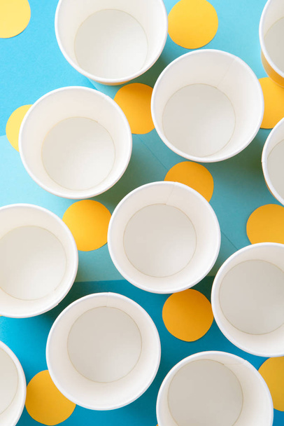 Желтые бумажные стаканчики для вечеринки на синем фоне
 - Фото, изображение