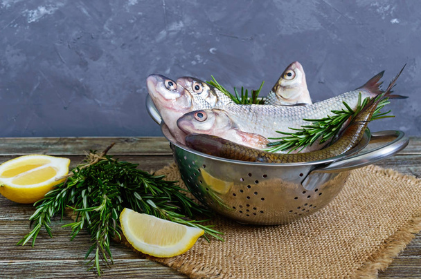Una pila de pescado fresco crudo con especias, limón, romero sobre un fondo de madera. Capturas frescas
. - Foto, Imagen