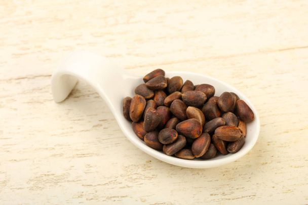 Cedar nuts heap in the bowl over wooden background - Foto, Imagen