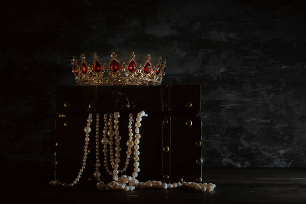 Image of mysterious opened old wooden treasure chest with light and queen/king crown with red Rubies stones. fantasy medieval period. Selective focus - 写真・画像