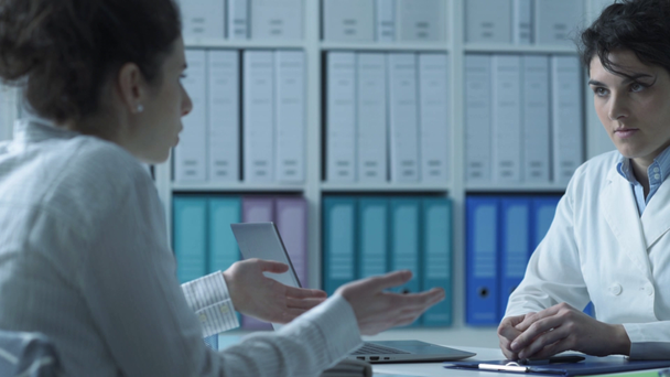 Γιατρός και ασθενής συνεδρίαση στο γραφείο, ο γιατρός είναι κάθεται στο γραφείο και ακρόαση - Πλάνα, βίντεο