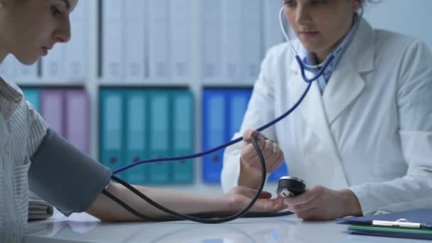 Doctor measuring a patient's blood pressure using a sphygmomanometer, hypertension and medical exams concept - Materiaali, video