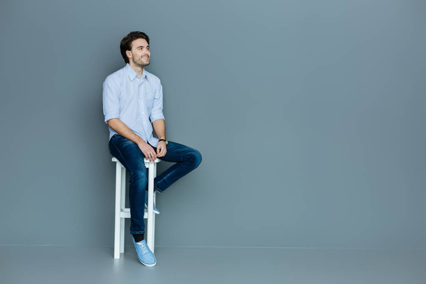 Joyful positive man sitting on a stool - Fotó, kép