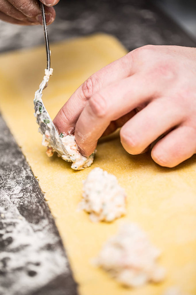 Chef's hands prepares Italian food stuffed pasta ravioli - 写真・画像