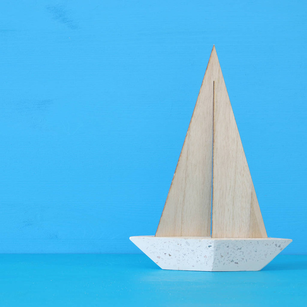 nautical concept with white decorative sail boat over blue wooden table and background. - Foto, immagini