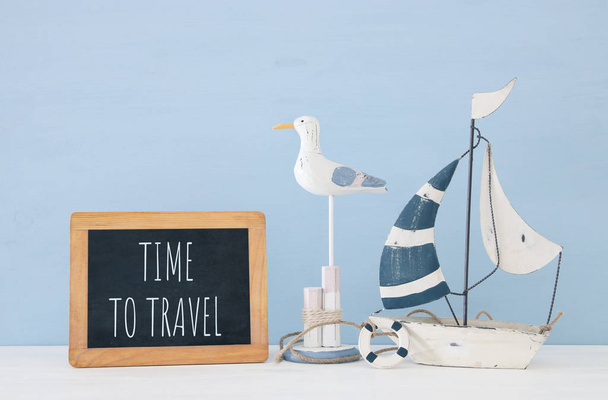 nautical concept with white decorative seagull bird, blackboard and boat over wooden blue background. - Foto, immagini