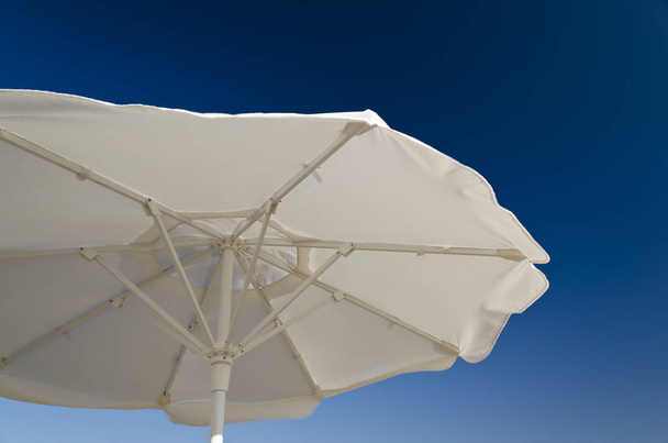 Plážový deštník proti modré jasné obloze na pláži - Fotografie, Obrázek