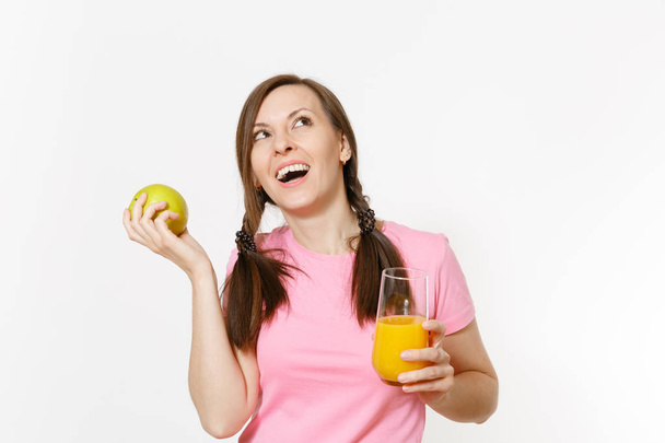 Mooie leuke gelukkige vrouw holding in handen groene appel en verse sinaasappelsap in glas geïsoleerd op een witte achtergrond. Goede voeding, op dieet zijn concept. Kopiëren van ruimte voor reclame. Gebied van de reclame. - Foto, afbeelding
