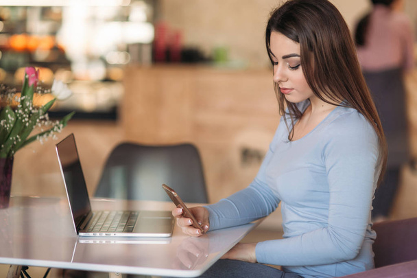 Красивая брюнетка бизнес женщина использовать телефон в кафе с ноутбуком
 - Фото, изображение
