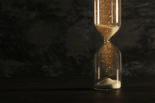 Imagen del reloj de arena como concepto que pasa el tiempo sobre fondo negro para la fecha límite del negocio. Superposición de purpurina
. - Foto, imagen
