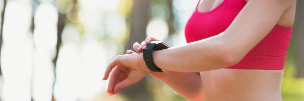 Attractive female athlete using fitness app on her smart watch to monitor workout performance. Web banner. - Foto, Imagen