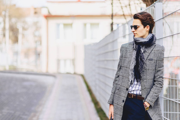 Stylish boy in sunglasses in coat with briefcase on street - Fotó, kép