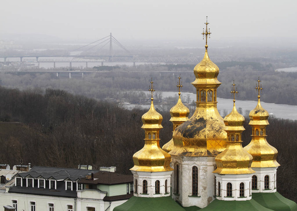 Dômes d'or de l'église de la Toussaint à Pechersk Lavra i Kiev, Ukraine. Sur le fond le pont Pivnichnyi qui traverse la rivière Dniepr
.  - Photo, image