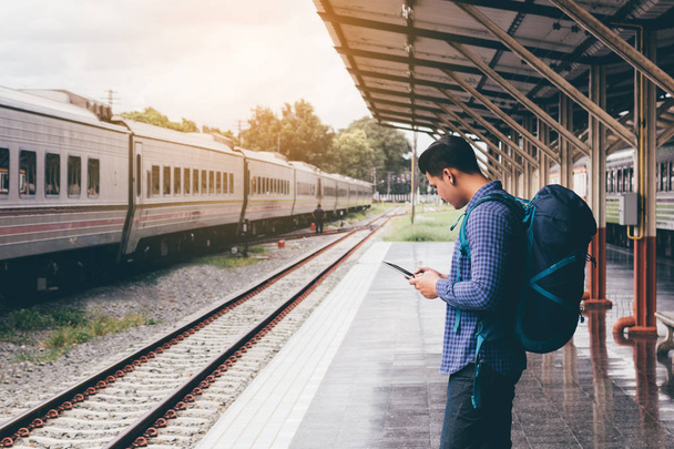 Azjatycki człowiek plecak podróż na dworzec kolejowy i za pomocą tabletu  - Zdjęcie, obraz