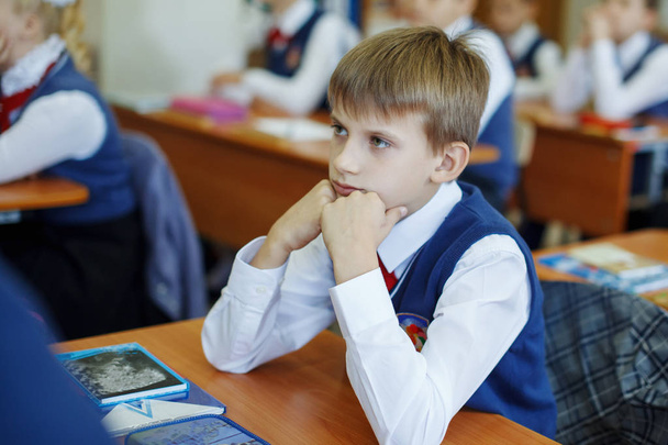 Bellissimo bambino della scuola a una scrivania in vacanza. Ottiene l'istruzione nella scuola primaria
 - Foto, immagini