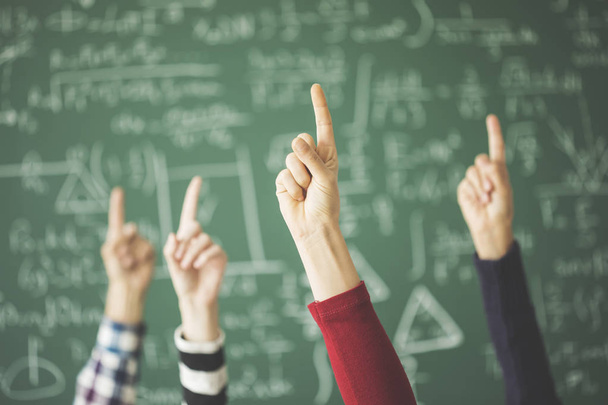 Студенты подняли пальцы на зеленую доску в классе
 - Фото, изображение