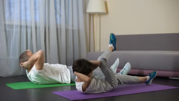 Father with son doing abdominal crunches at home, showing benefit of sports - Séquence, vidéo