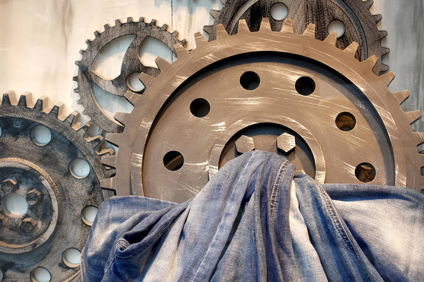 Concept of production of jeans. Jeans and metal gears on a wooden background.                   - Photo, Image