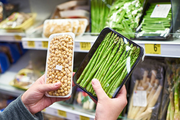 Hands with asparagus and sprouted peas in shop - Фото, изображение