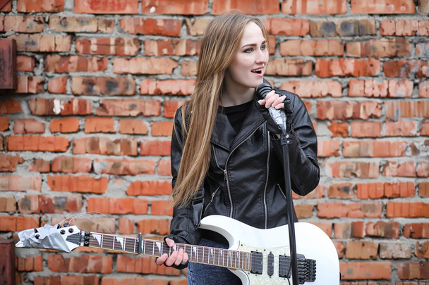  Рок-музыкантка в кожаной куртке с гитарой
  - Фото, изображение