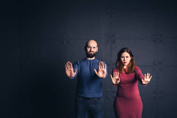 bearded man and pregnant woman show hands stop in studio on dark background. Copy space. - Fotografie, Obrázek