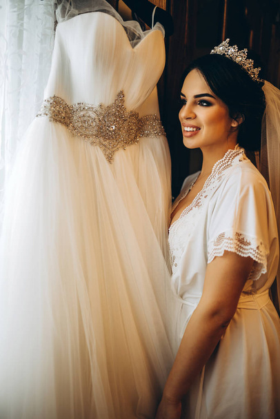 Smiling bride dressing up before wedding ceremony - Фото, изображение