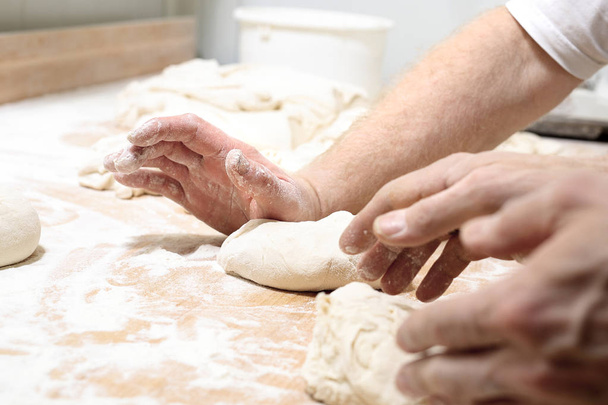 Pizza dough. The man kneads the dough. - Fotó, kép