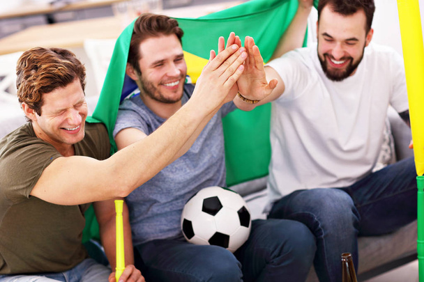 Happy male friends cheering and watching sports on tv - Photo, Image