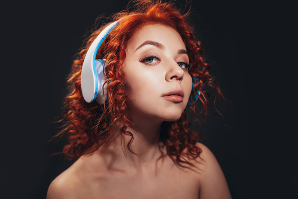 Beautiful redhead curly girl portrait close up with headphones - Fotó, kép