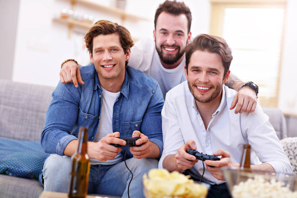 Friends having fun on the couch with video games - Foto, Bild