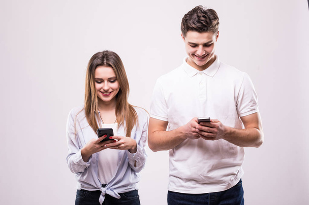 Glückliches Paar blickt auf Smartphone isoliert auf grau - Foto, Bild