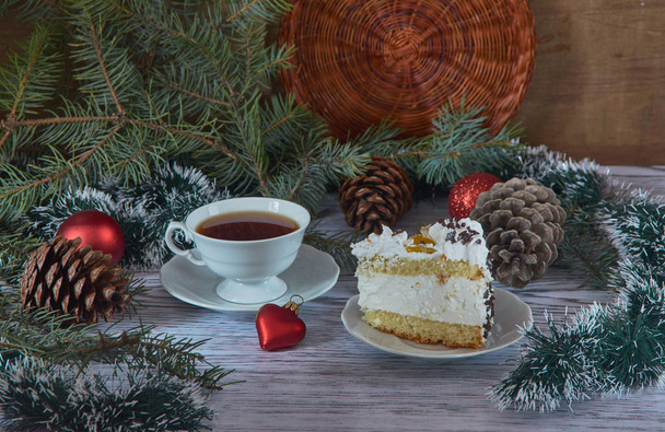 A cup of tea with a piece of cake surrounded by festive New Year's decorations. - Foto, Bild