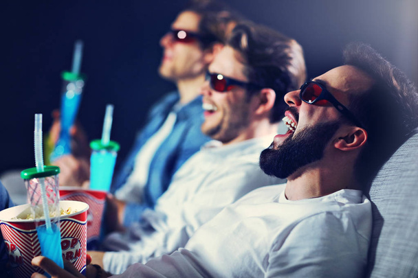 Group of happy friends sitting in cinema watch film and eating popcorn - Fotoğraf, Görsel