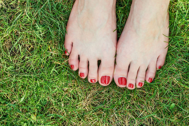 a zöld fű, vörös körmök női láb - Fotó, kép