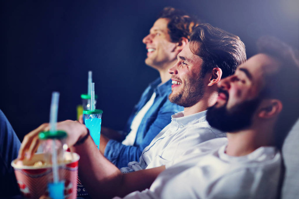 Group of happy friends sitting in cinema watch film and eating popcorn - Фото, зображення
